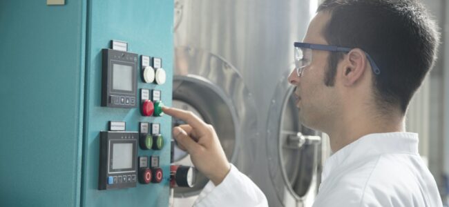 Chemist in a technical room pushing a button